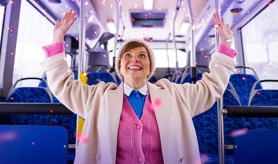 Nainen iloitsee bussissa. 