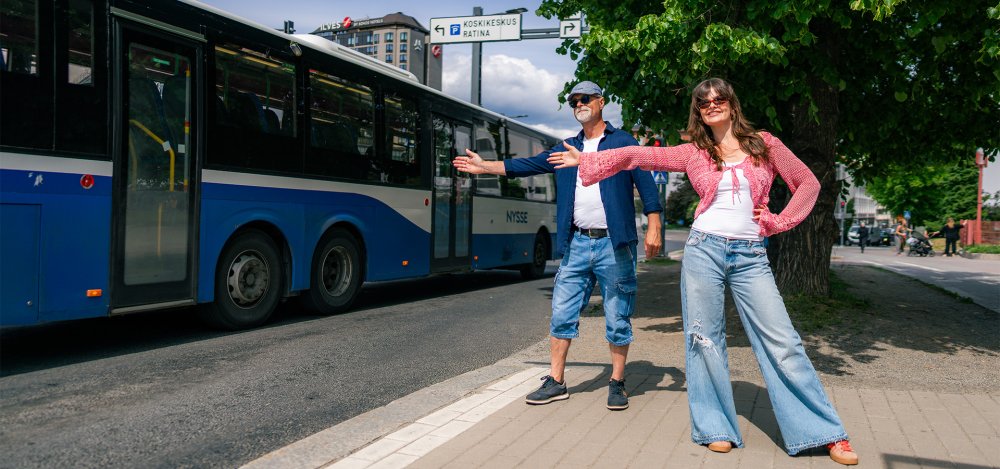 Mies ja nainen heilauttavat kättään Nyssen bussille kadun varrella, Tampereen keskustassa. 
