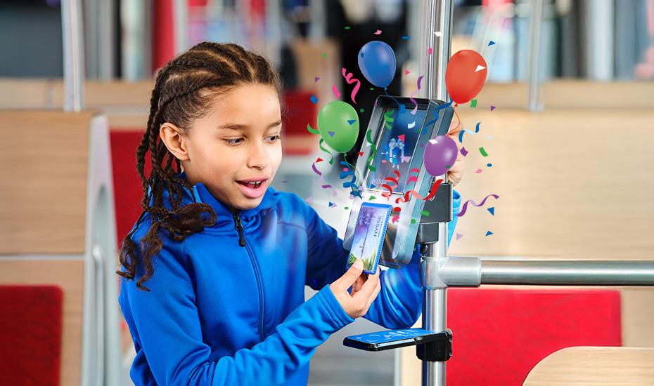 Poika näyttää Nyssen matkakorttia lippulaitteella, josta lennähtää ilmaan ilmapalloja ja serpentiiniä. 