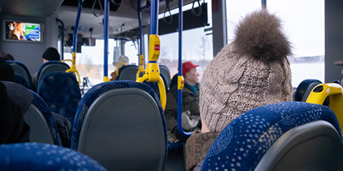 Matkustaja istuu pipo päässä bussissa.