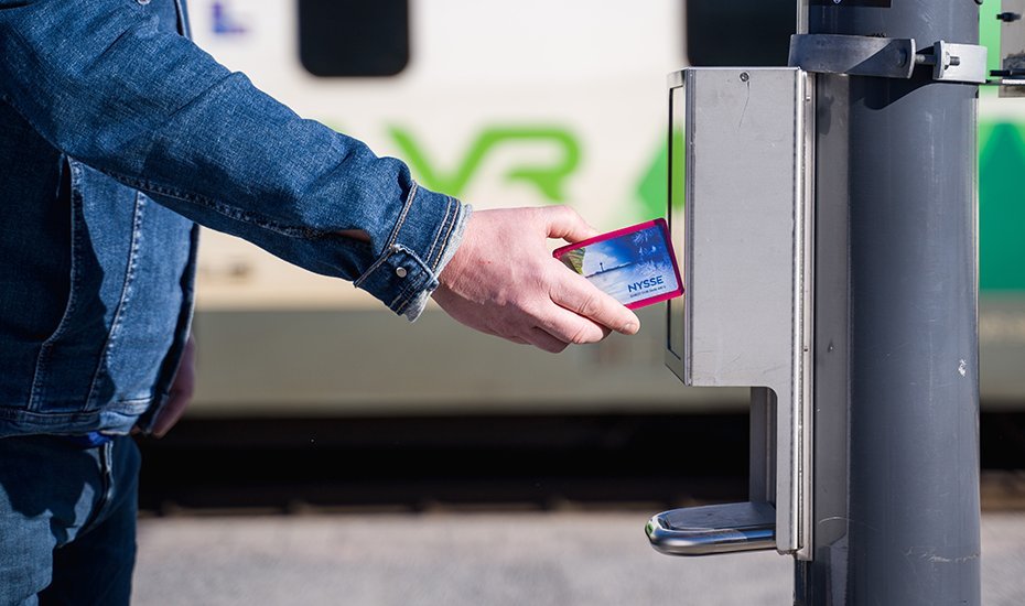 A passenger is setting his travel card on the ticket device at the railway station platform.