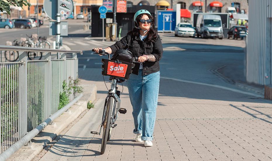 Nainen taluttaa kaupunkipyörää Laukonsillalla.