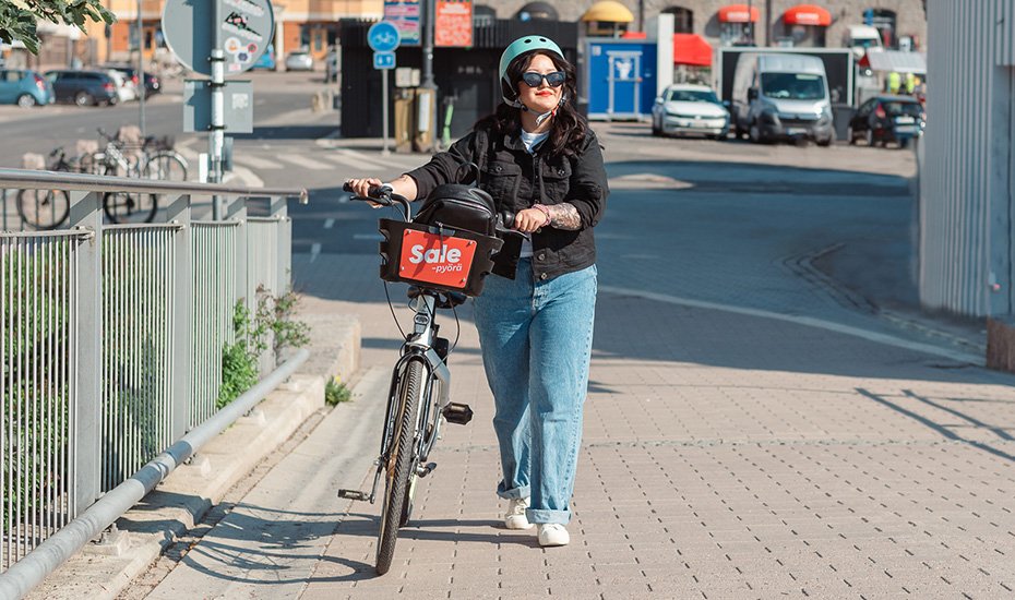 Nainen taluttaa kaupunkipyörää Laukonsillalla.