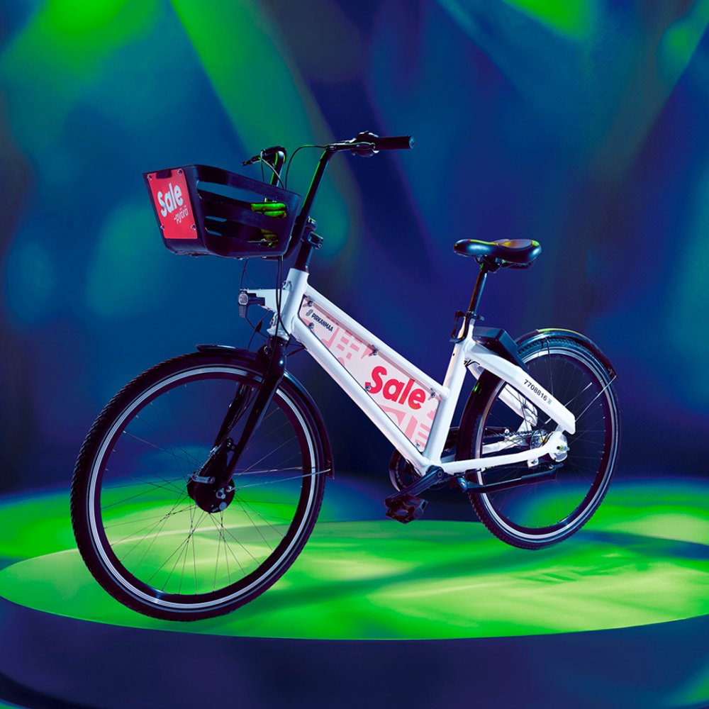 Tampereen kaupunkipyörässä on valkoinen runko ja musta satula, ohjaustanko ja kori. Korissa ja rungossa on Sale-pyörä-kyltit.