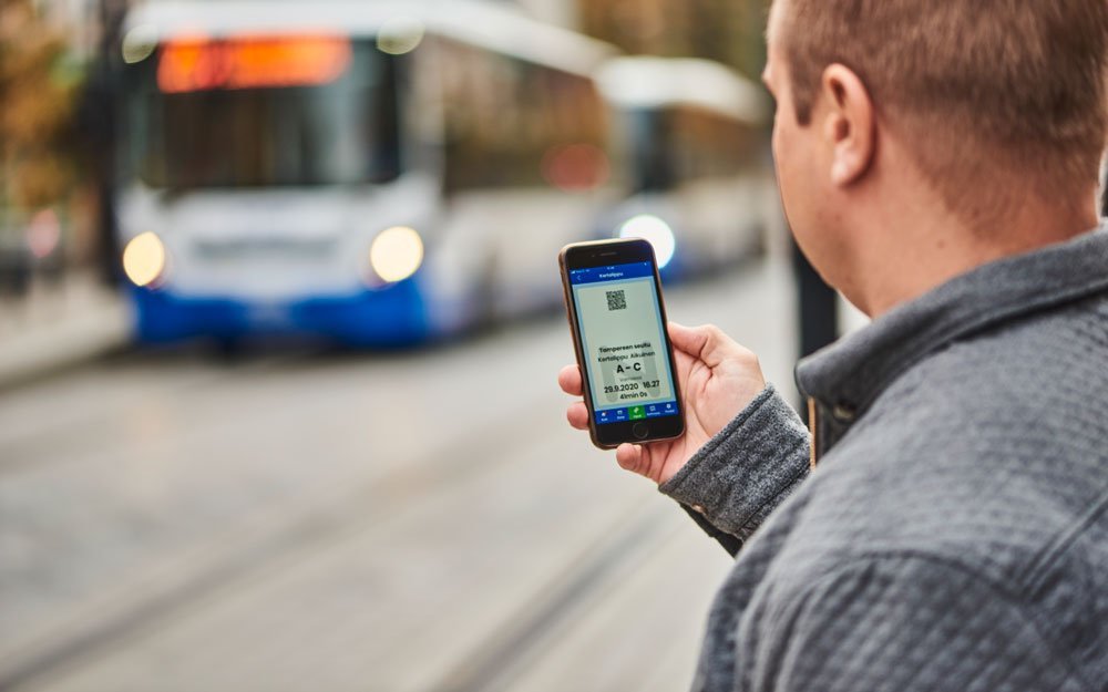 Matkustaja ostaa mobiililipun Nysse Mobiilisovelluksesta. Bussi on saapumassa pysäkille.