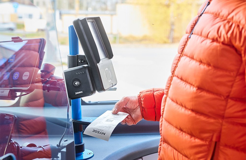 Matkustaja näyttää ennakkokertalipun QR-koodia lippulaitteen lippulaitteen pohjassa olevaan lukijaan.