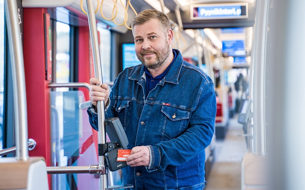 Matkustaja käyttää maksuvälineen ratikan lippulaitteella.