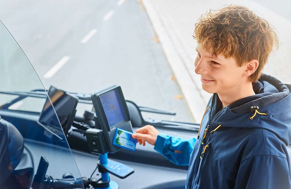 Matkustaja käyttää matkakorttia lippulaitteen etumaisessa lukijassa.