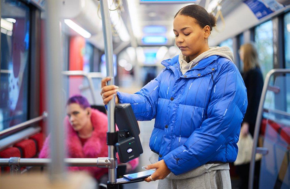 Matkustaja näyttää mobiililipun QR-koodia lippulaitteen lippulaitteen pohjassa olevaan lukijaan.