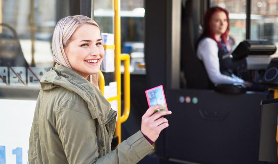 Nuori matkustaja astumassa bussiin matkakortti kädessä. 