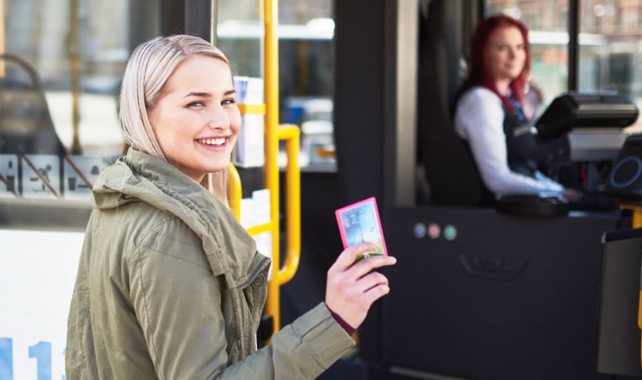 Nuori matkustaja astumassa bussiin matkakortti kädessä. 