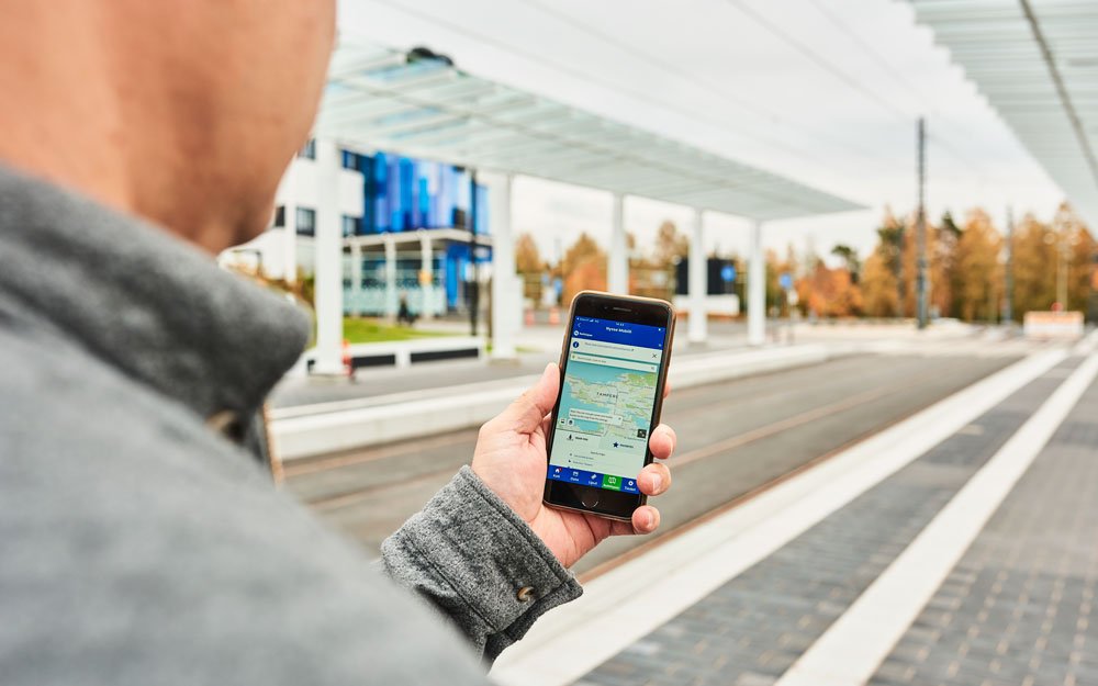 A traveller is checking schedules in the Journey Planner at Kauppi campus joint bus and tram stop.