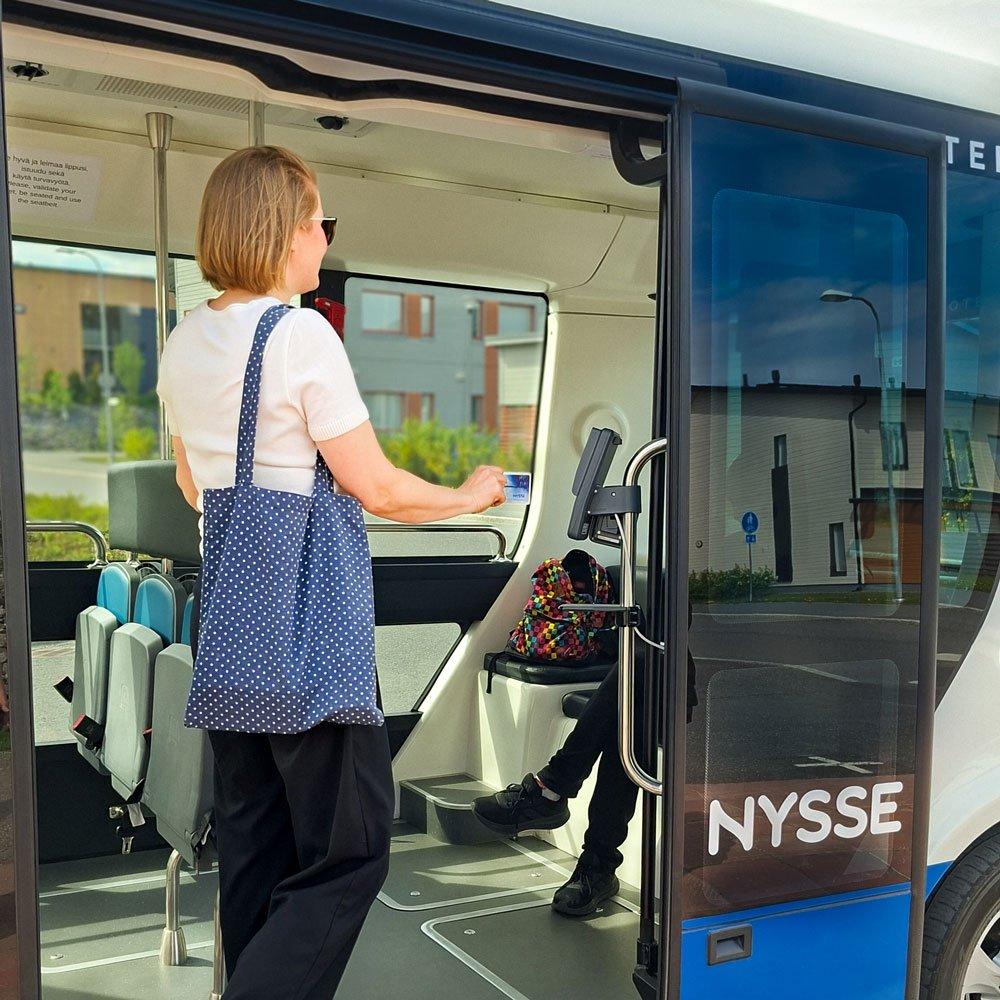 Matkustaja leimaa matkalippua robottibussissa. Lippulaite on heti oven vieressä.