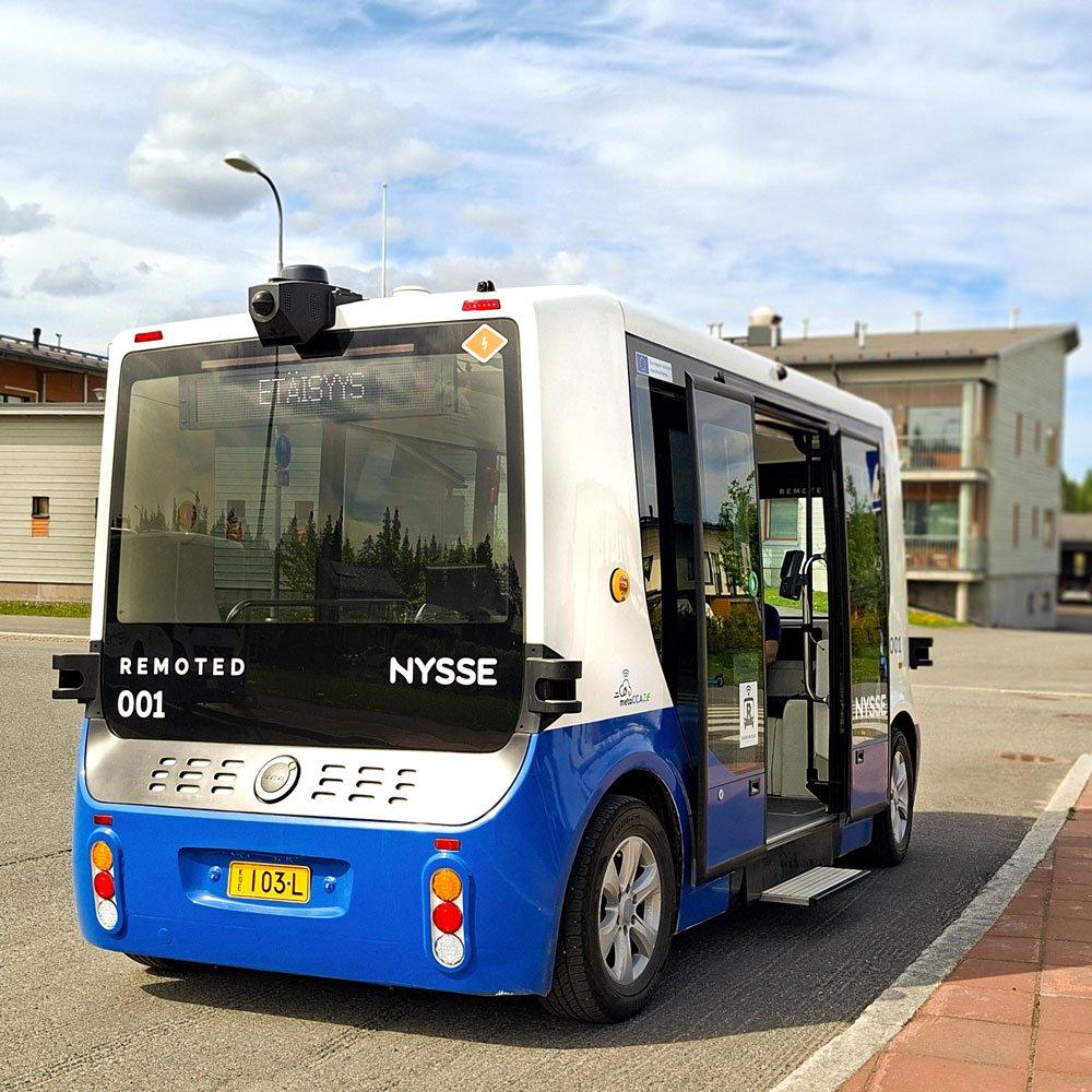 Robottibussi odottaa lähtöä Lintuhytin pysäkillä. Ovi on auki ja sen edessä on pieni, ulosliukuva apuporras.