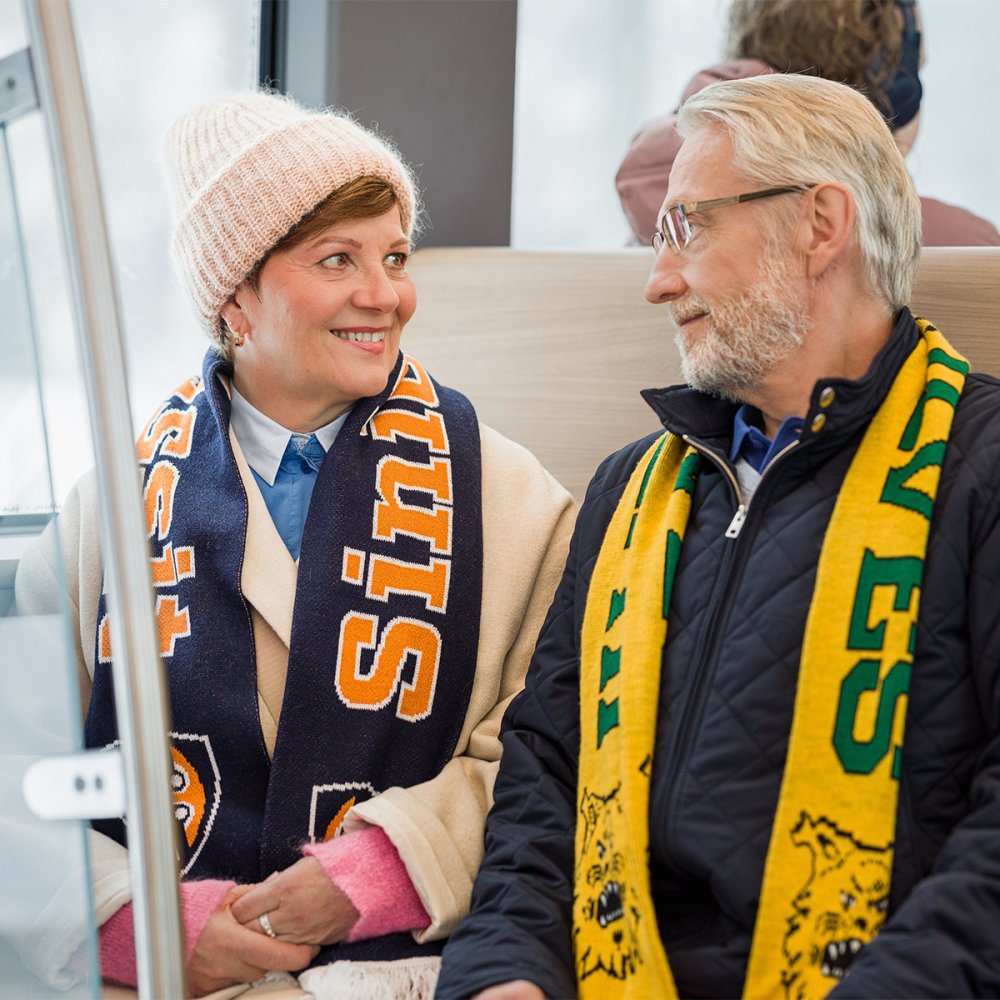 Two passengers, one wearing a Tappara scarf and one wearing an Ilvek scarf.