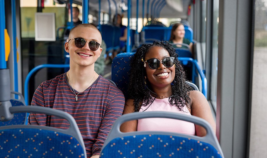 Tyttö ja poika hyväntuulisina bussissa.
